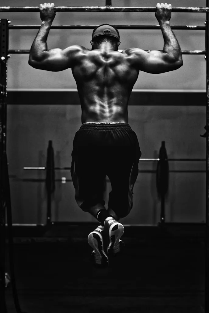 An athlete doing a pull-up, seen from behind